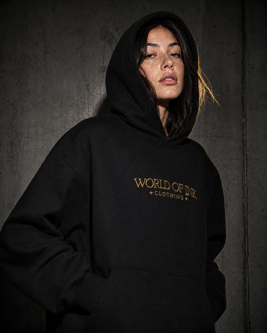 Model im schwarzen Heavy Hoodie mit Gold-Stickerei
